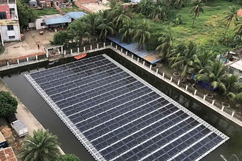 Elevated view of AKH Fashions floating solar array with city backdrop in Bangladesh